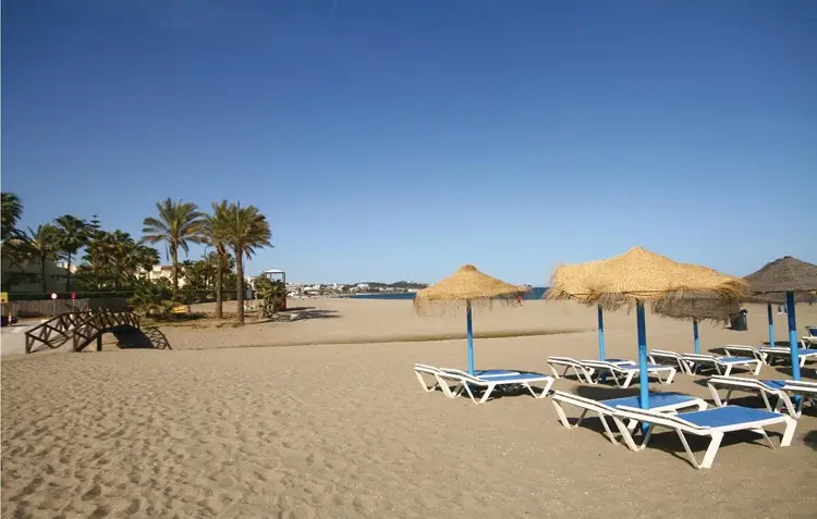 Strand van La Cala de Mijas bij Royal Palms met ligbedden en palmbomen